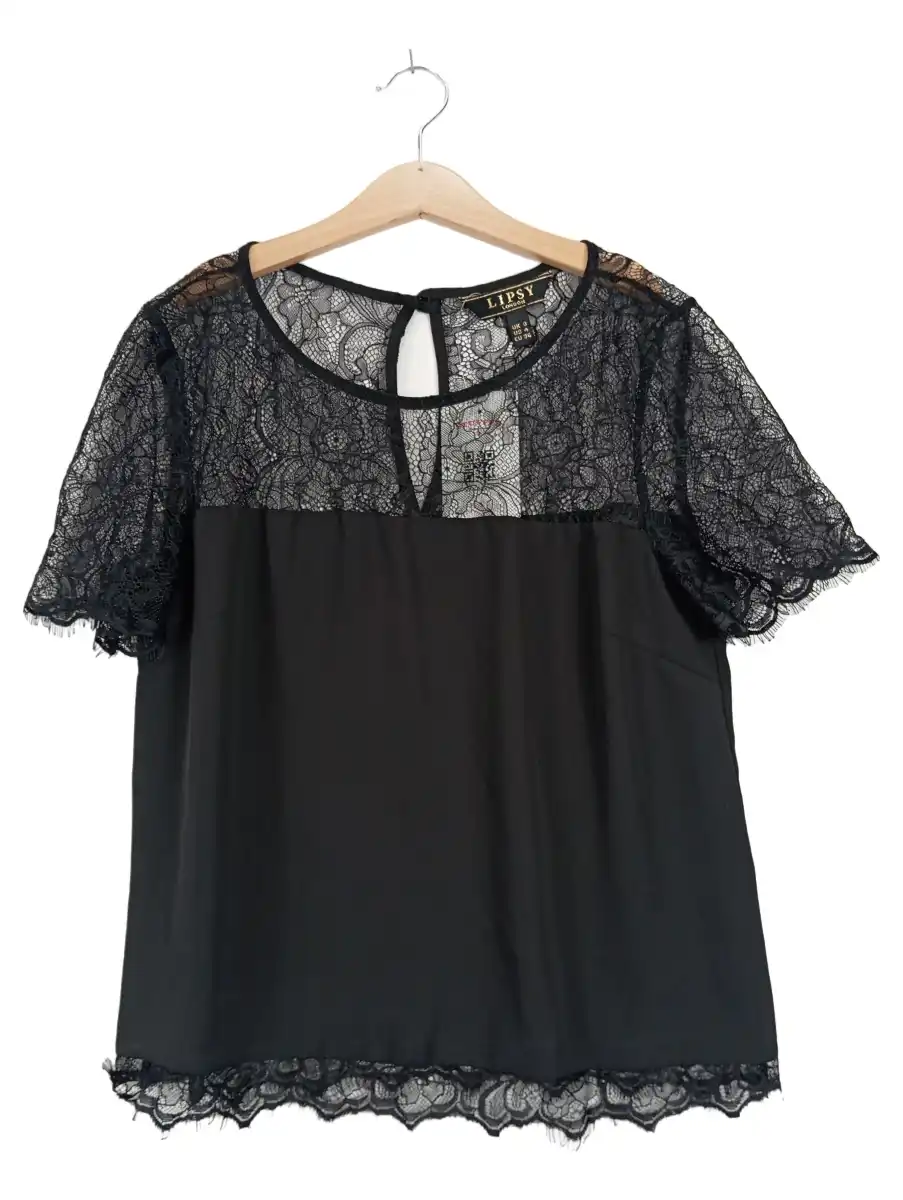 Schwarze Spitzenbluse mit Blumenmuster auf einem Bügel